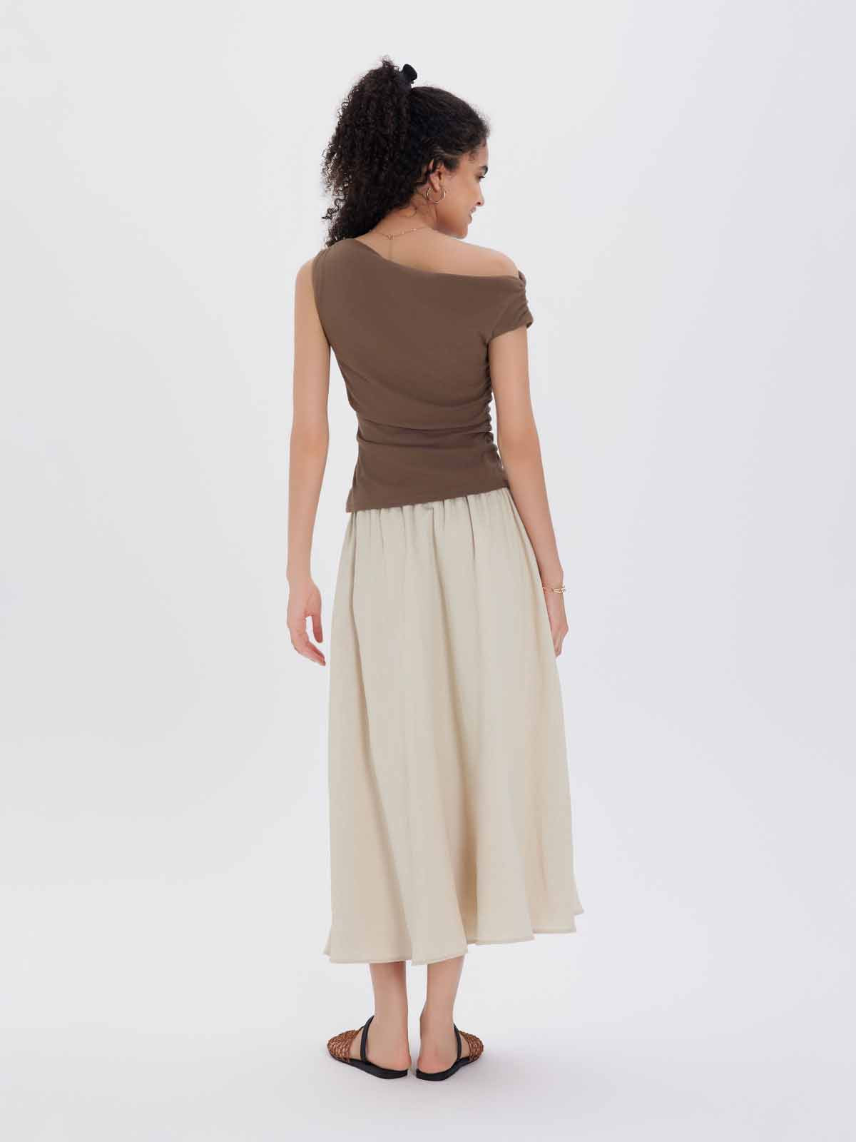 A brown one-shoulder top and beige skirt
