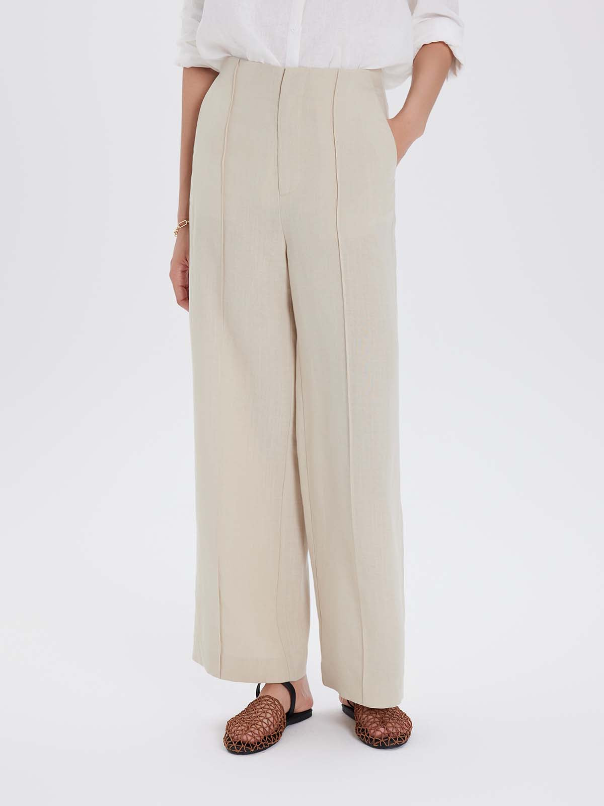 Person wearing beige wide-leg pants and a white top on a white background